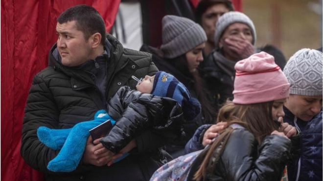 An Uzbek man holds a baby at a Polish reception centre for people evacuated from Ukraine