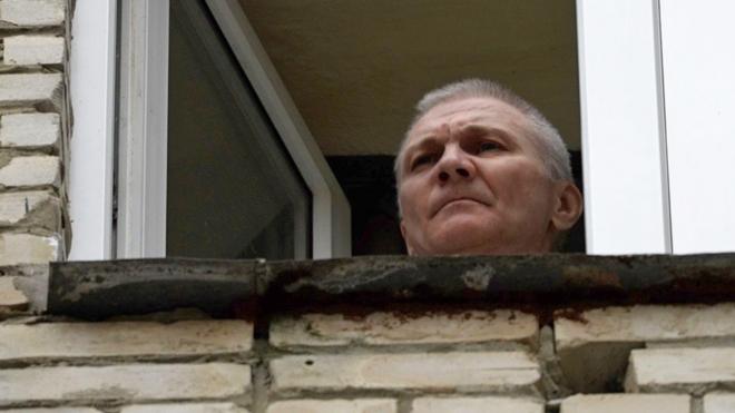 Alexei Moskalev appears at a window of the building where he is being held under house arrest