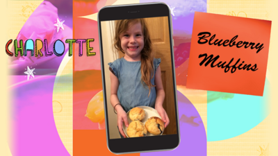 A little girl called Charlotte smiles as she holds up a plate of blueberry muffins