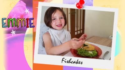 A little girl (Emmie) posing with a plateful of fishcakes and green veggies.