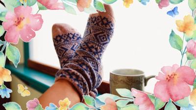 some feet in socks resting up in the windowsill with a cup of tea.