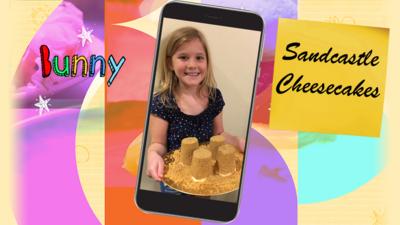 A girl with a plateful of what looks to be sandcastles, with a sign saying 'Sandcastle Cheesecakes.'