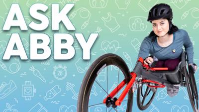 Blue Peter's Abby sits in her racing wheelchair wearing a black helmet. Text reads: Ask Abby