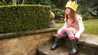 Young girl dressed in a crown and wellies