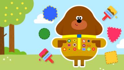 Duggee standing next to lots of badge pieces.