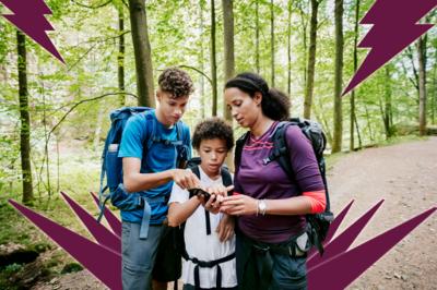 Picture of a mother and two sons looking at a phone while hiking in the woods