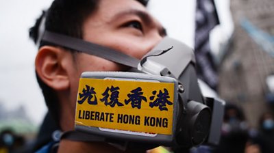 Protester wearing gas mask with 'Liberate HK' sticker
