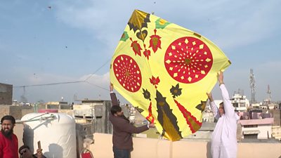 Two men holding a giant kite about to release it