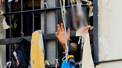 A prisoners hand reaches through prison bars