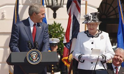 George W. Bush looks sheepishly at Queen during a speech