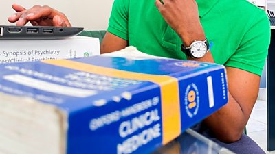 shot of medical books and black man in background