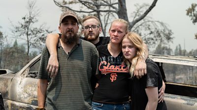 Family stands in remains of burned home