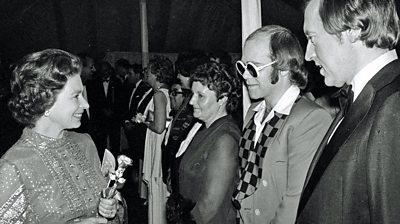 A photo taken in 1977 of pop star Sir Elton John and television personality David Frost meeting Queen Elizabeth II