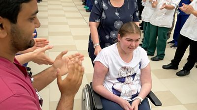 Freya in a wheelchair being clapped out of hospital