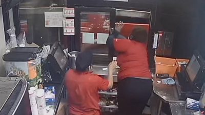 Woman leans out through drive through window as car speeds away