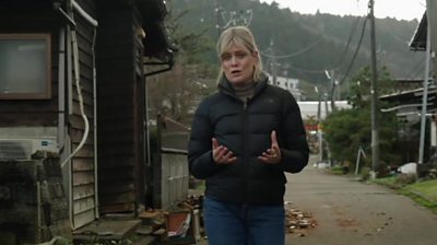 Jean MacKenzie walks along road with damaged buildings on either side