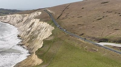 Cars pass close to the cliff edge on Military Road