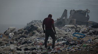 Man standing over pile of rubbish
