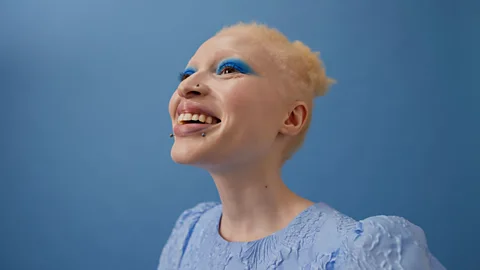 Albino woman smiling against blue background