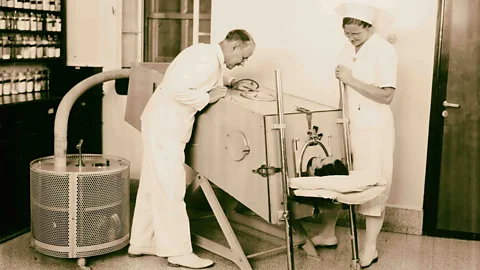 man in iron lung with two health workers in 1900s (Credit: Getty Images)
