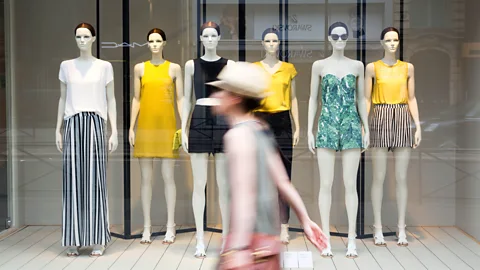 Woman walks in front of store window (Credit: Getty Images)