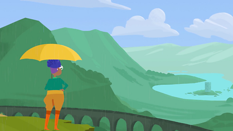 Sue holding an umbrella and looking at some mountains, a bridge and lake.