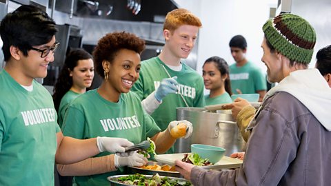 Volunteers wearing a green t-shirt working in a soup kitchen