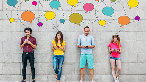 Social network concept. Young people texting with smart phones in front of a big stone wall with a lot of coloured speech bubbles showing above them.