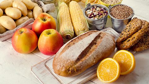 A selection of complex carbohydrates such as bread, apples, oranges, potatoes and grains