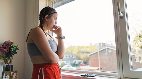 Girl looks out of her window appearing worried