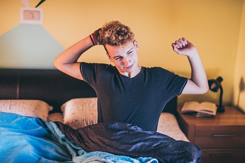 Teenager stretching in bed after waking up