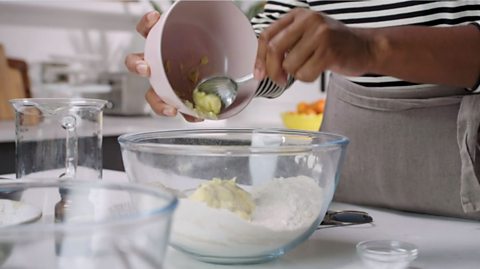 Adding butter to a bowl of flour 