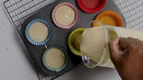Cupcake mixture being poured into cupcake cases