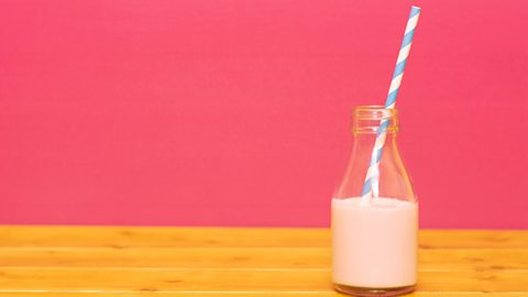 Glass bottle of milk with straw in it 