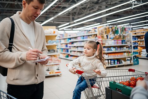 Father looking at shopping list whilst shopping with his daughter