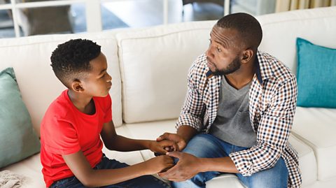 dad speaks with his son sat on the sofa