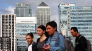 People walk next to London's financial district at Canary Wharf in London
