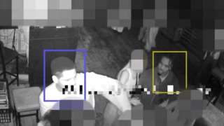 CCTV still of two men with other people