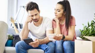 Couple looking at mobile and bills