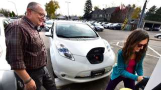 Man and woman learning how to charge second hand electric car