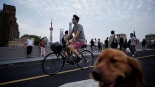 A man wearing a protective face mask cycles past people and a dog on a bridge, as the city prepares to end the lockdown placed to curb the coronavirus disease (COVID-19) outbreak in Shanghai, China May 31, 2022.