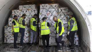 Workers unload flowers from a plane at Miami International Airport on February 08, 2022