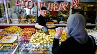 A woman buys pastries in Marrakesh, Morocco, for Eid al-Fitr