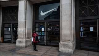 A woman reads the sign on the door of the closed Niketown store on Oxford Street, London.