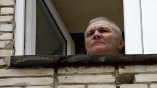 Alexei Moskalev appears at a window of the building where he is being held under house arrest