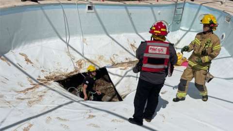 Emergency workers at scene of swimming pool sink hole