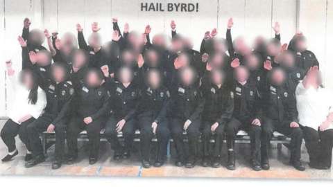 Employees at the West Virginia Division of Corrections and Rehabilitation giving the salute below a sign that reads "HAIL BYRD!"