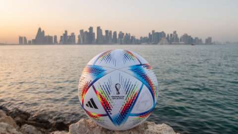 A World Cup football with the Qatar skyline in the background