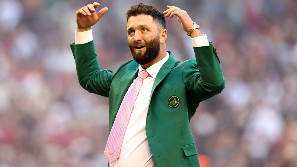 Golfer Jon Rahm, wearing his Green Jacket after winning the Masters, celebrates after throwing out the ceremonial first pitch