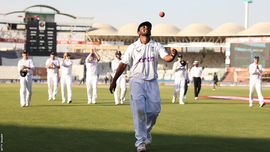 Rehan Ahmed tossing the ball into the air as he leads England off the field after taking five wickets